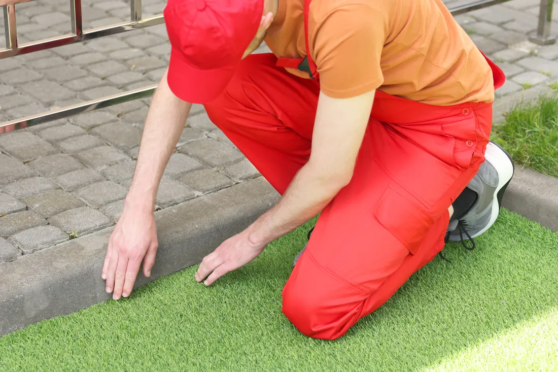 Artificial turf being trimmed to a garden edge during installation