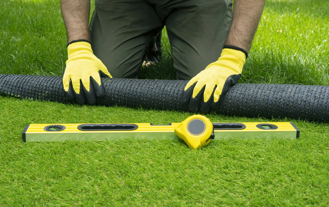 Installer measuring and levelling a prepared turf base